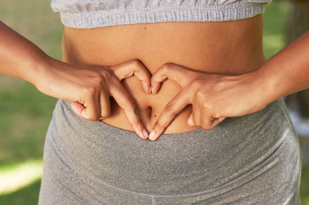Close up of multi-ethnic woman holding hands in heart over belly, body positive. High quality photo - Photo, image