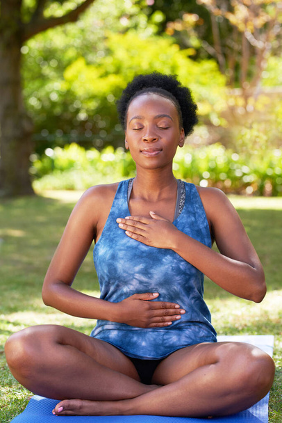 Joven hermosa mujer negra practica la respiración profunda del vientre en la esterilla de yoga al aire libre. Foto de alta calidad - Foto, imagen