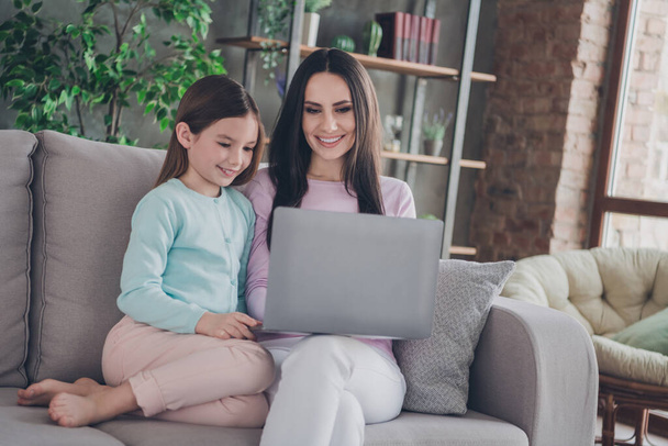 Photo of mommy sit cozy couch with kid girl use netbook browsing toy on website in modern apartment flat. - Photo, Image