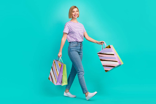 Full body photo of smiling girl wear denim with t-shirt hold bargains from new shopping center satisfied isolated on aquamarine background. - Fotografie, Obrázek