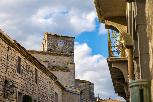 Bell tower of the Notre-Dame-de-l'Assomption church from an alley in the medieval village of Matelles - 写真・画像