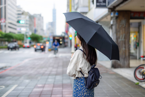 Frau mit schwarzem Regenschirm im Freien festgehalten - Foto, Bild