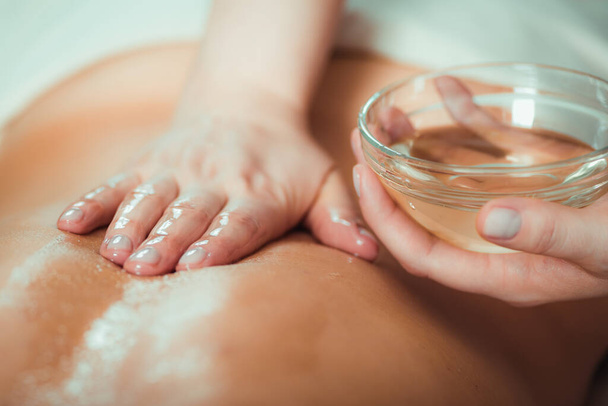 Massaging with massage oil, hands of a female massage therapist massaging a female client - Фото, изображение