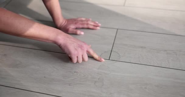 Mujer ama de casa señala con el dedo a la suciedad en el primer plano del suelo de laminado. Concepto de limpieza de alta calidad de apartamentos y oficinas - Imágenes, Vídeo