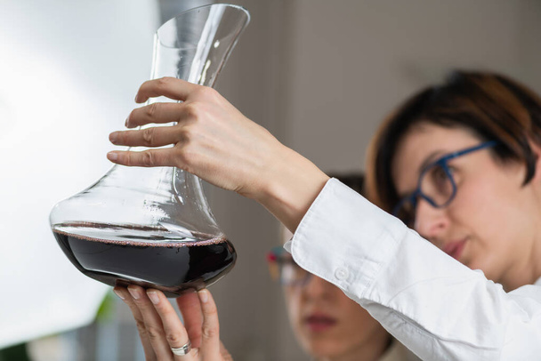 Degustacja wina, ocena jakości. Sommelier patrzy na wino w karafce i wyjaśnia, jak ocenić jego jakość na podstawie wyglądu, aromatu, smaku i wykończenia. - Zdjęcie, obraz