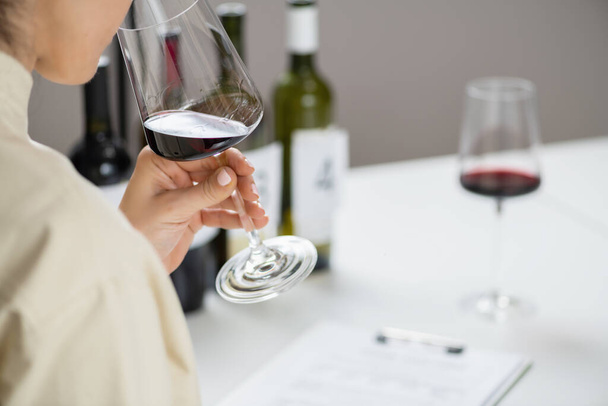 Degustación de vinos. Una mujer disfruta de una degustación de vino tinto, saboreando los sabores y aromas del vino. - Foto, Imagen