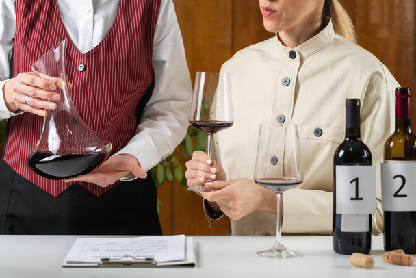 ワインの試飲イベント、品質評価。ソムリエがワインをデカンタで見て、見た目、香り、味、仕上げに基づいて品質を評価する方法を説明します。. - 写真・画像