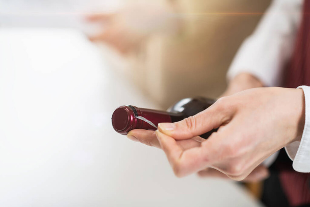 Weinverkostung. Der Sommelier entfernt die Folie, die den Deckel einer Weinflasche bedeckt, und erklärt, wie man eine Flasche Wein für den Service richtig zubereitet. - Foto, Bild