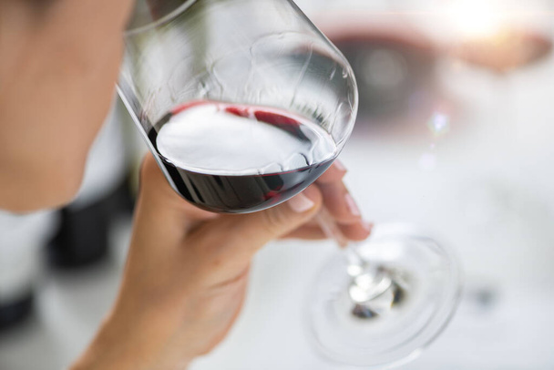 Şarap tatma. Bir kadın kırmızı şarap tatmaktan, şarabın lezzetlerinden ve aromalarından zevk alır.. - Fotoğraf, Görsel
