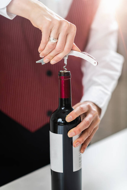 Cursus wijnonderwijs. Een sommelier demonstreert hoe een kurkentrekker in de kurk kan worden gestoken, wat een fundamentele vaardigheid is om een fles wijn te openen.. - Foto, afbeelding