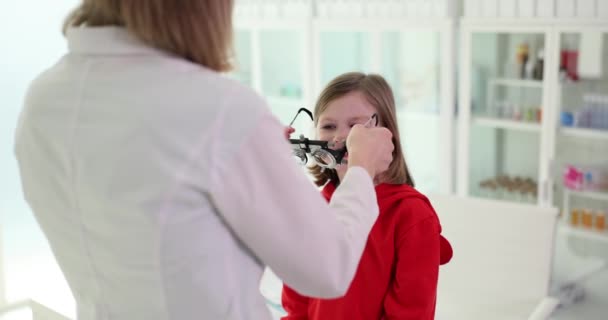 L'oftalmologo diagnostica la visione della bambina e seleziona le lenti. Cliniche per il trattamento e la correzione della vista - Filmati, video