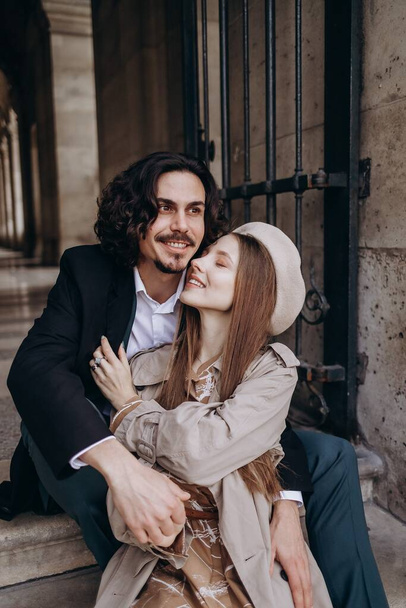 Zamilovaný pár kráčí ulicemi Paříže, muž v kabátě a obleku, dívka v šatech s baretem a pláštěm na podzim - Fotografie, Obrázek