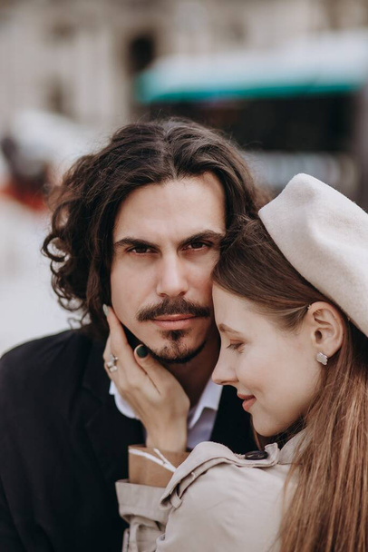 Una coppia innamorata cammina per le strade di Parigi, un ragazzo con un cappotto e un vestito, una ragazza con un vestito con un berretto e un trench in autunno - Foto, immagini