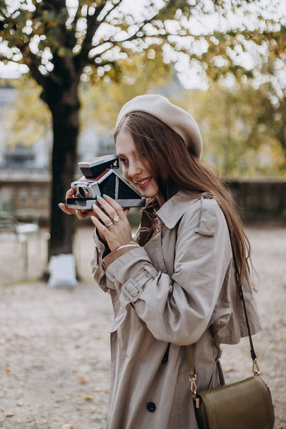Zamilovaný pár kráčí ulicemi Paříže, muž v kabátě a obleku, dívka v šatech s baretem a pláštěm na podzim s kamerou - Fotografie, Obrázek