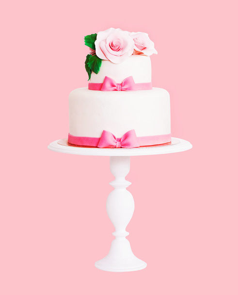 Торт украшен розами и луками на белом подставке
 - Фото, изображение