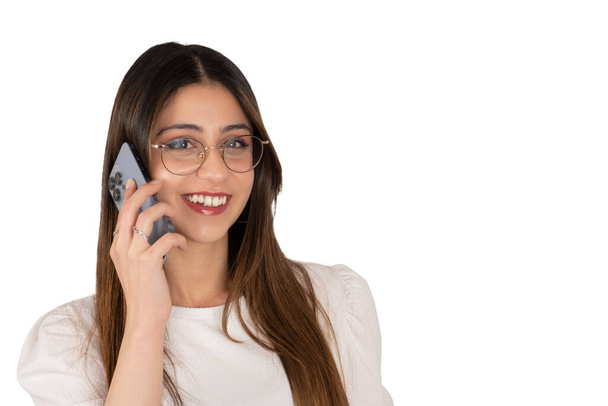 Talking by modern smartphone, portrait of brunette  caucasian young woman talking by modern smartphone. Looking camera. Positive lady. Isolated white background. Wearing glasses calling her friend. - Fotó, kép