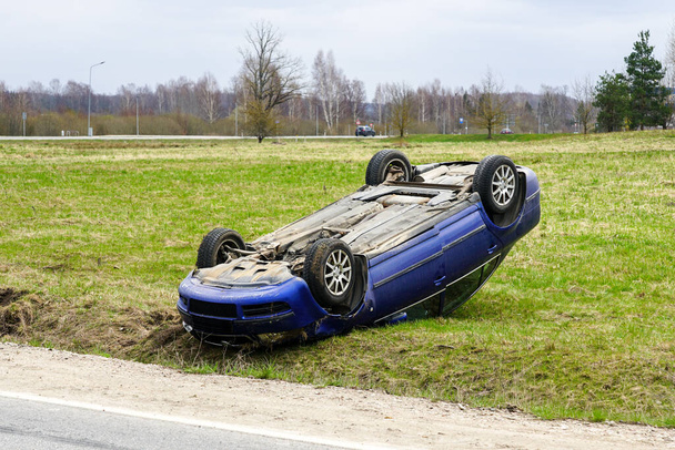 Сцена автокатастрофи, пасажирський автомобіль пішов з дороги і перекинув колеса вгору, перекинутий автомобіль
 - Фото, зображення