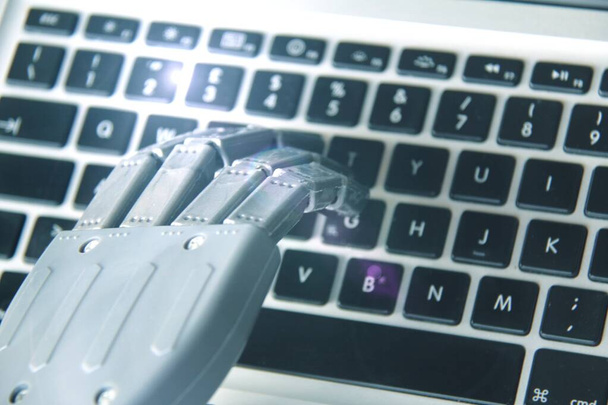 Рука робота во время работы на клавиатуре компьютера . - Фото, изображение