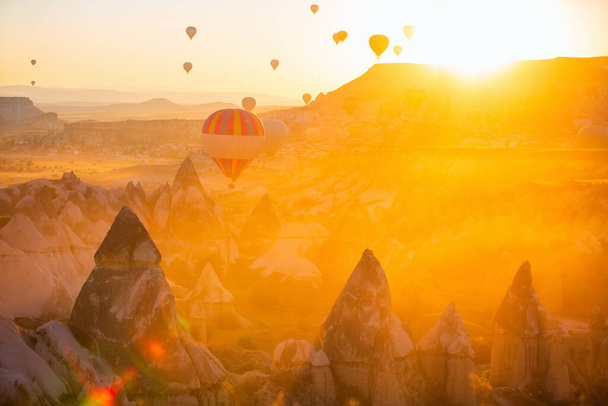 Gorgeous sunrise scenery of hot air balloons flying over Love valley with rock formations and fairy chimneys in Cappadocia Turkey - Foto, imagen