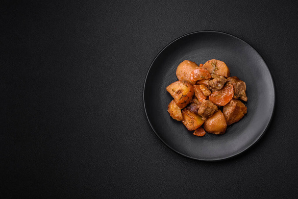 Heerlijke verse stoofpot met varkensvlees of rundvlees met aardappelen, wortelen, specerijen en kruiden op een donkere betonnen ondergrond - Foto, afbeelding
