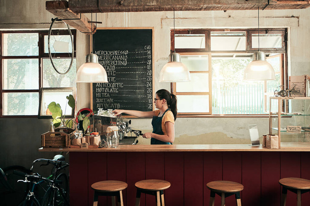 She makes the best coffee in town. a young barista working in her coffee shop - 写真・画像