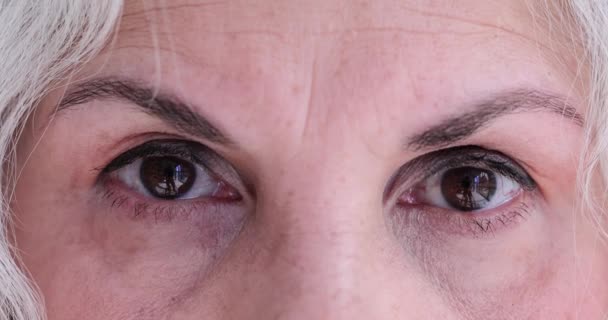 Μακροσκοπική λήψη ηλικιωμένης γυναίκας με καστανά μάτια που κοιτάζει την κάμερα. ρυτίδες ματιών και κρεατοελιές σε μεγάλη ηλικία - Πλάνα, βίντεο