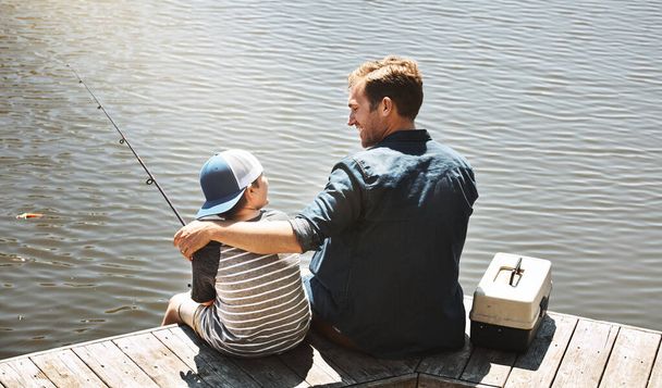 Balıkçılık onların kaçışıdır. Bir babanın ve küçük oğlunun birlikte balık tutarken çekilmiş bir fotoğrafı. - Fotoğraf, Görsel