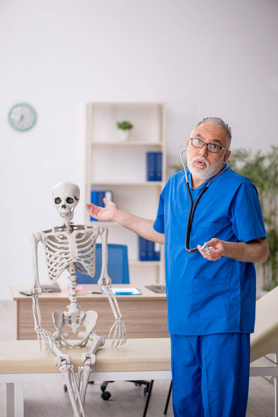 Viejo doctor examinando esqueleto en el hospital - Foto, Imagen