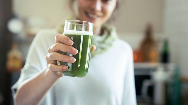 Young woman drinks a glass of green healthy smoothie - Foto, immagini