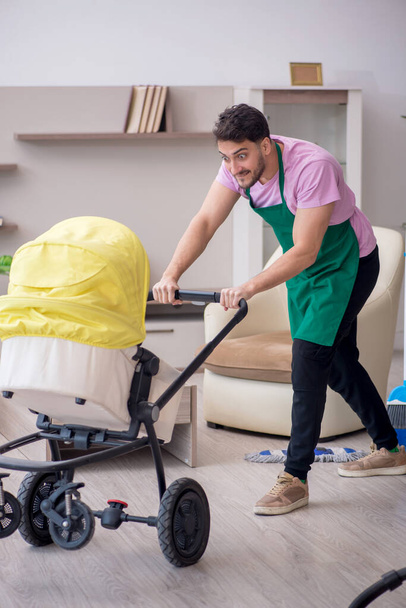 Young contractor cleaner looking after newborn - Foto, afbeelding