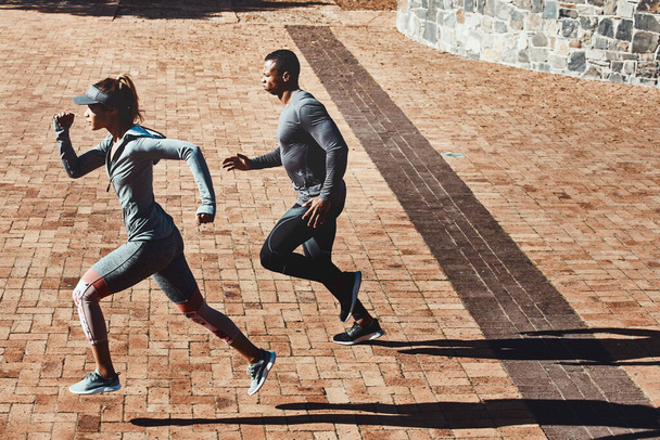 Their favourite way to start the day. Full length shot of two young and athletic young people running through the city - Fotoğraf, Görsel
