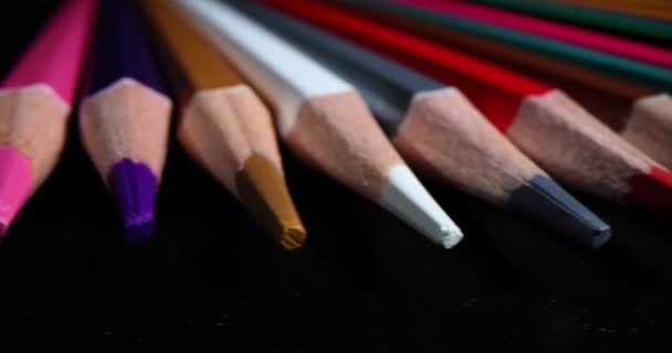 Crayons multicolores fortement aiguisés sur fond noir. Crayons d'art colorés gros plan - Séquence, vidéo