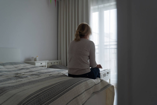 Mature woman sitting alone in the room, sad depressed person. Back view. mental health problemageing population. High quality photo - Foto, Bild