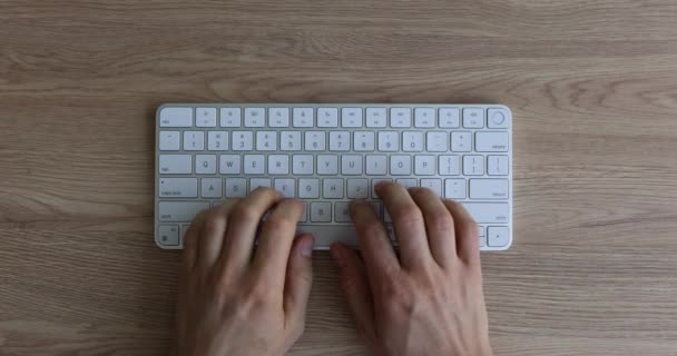 Mężczyzna wpisując na białej klawiaturze za pomocą komputera w miejscu pracy w biurze widok z góry. Pracownik IT pracuje palec i wyszukiwarki internetowej asystent - Materiał filmowy, wideo