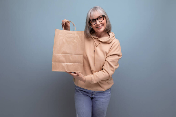 mulher de negócios de meia idade com cabelos grisalhos segurando um pacote para seguro de aposentadoria em um fundo de estúdio com espaço de cópia. - Foto, Imagem