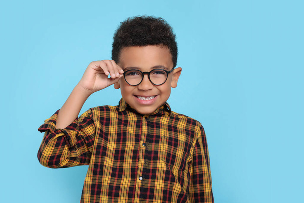 Cute African-American boy with glasses on turquoise background - Φωτογραφία, εικόνα