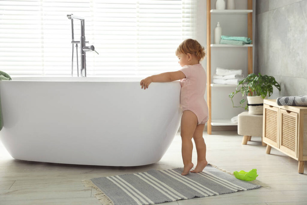 Cute little girl near tub in bathroom - Foto, imagen