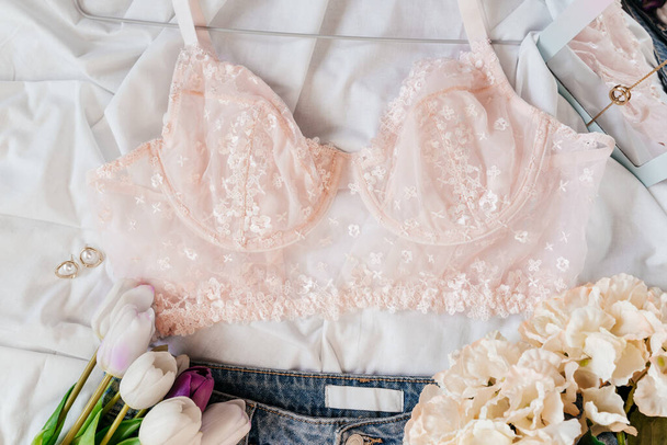 Gentle pink lace bra on the bed. Women tender lingerie, underwear. Top view, close up. Flat lay, beauty blog or social media minimal concept. Present for Valentines, Womens day - Photo, Image