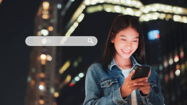 Aasialaiset naiset käyttävät älypuhelimia löytääkseen mitä he ovat kiinnostuneita kaupungin yöelämästä. Haetaan tietoa internetin verkottumisen käsitteestä - Valokuva, kuva