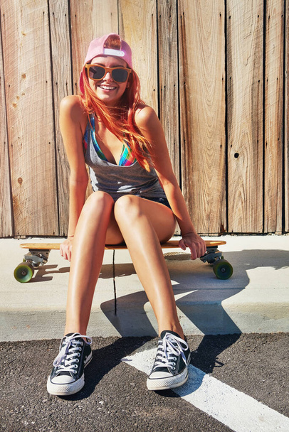 Chcę gdzieś wyskoczyć. młoda kobieta siedząca na deskorolce na chodniku - Zdjęcie, obraz