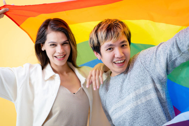 Happy Asian man and caucasian white woman portrait in LGBTQ+ with rainbow flag concept. - Zdjęcie, obraz