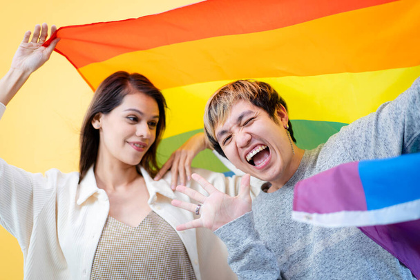 Happy Asian man and caucasian white woman portrait in LGBTQ+ with rainbow flag concept. - Foto, imagen