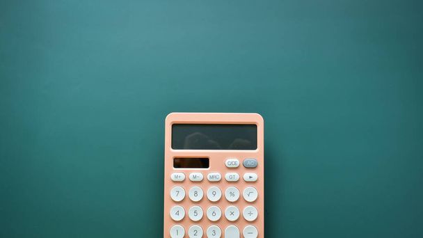 calculadora pastel cor pêssego moderno e botão branco no fundo verde, conceito de contabilidade de negócios e finanças - Foto, Imagem
