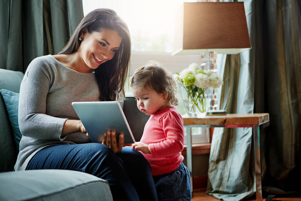 Технології можуть підвищити розвиток раннього дитинства. мати і її чарівна маленька дочка використовують цифровий планшет вдома
 - Фото, зображення