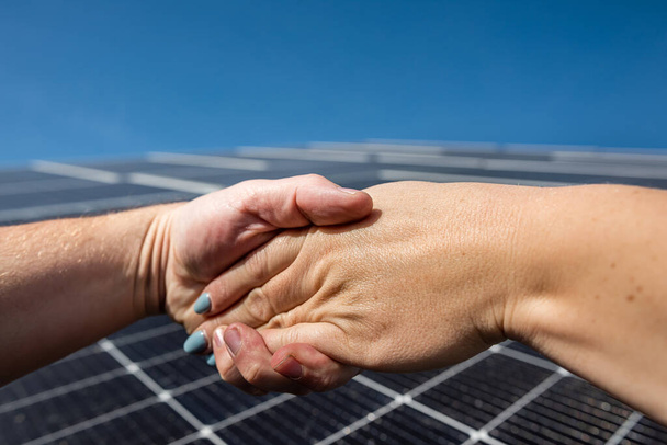 屋外の太陽光発電パネルの前で握手。太陽光パネルを設置する前に - 写真・画像