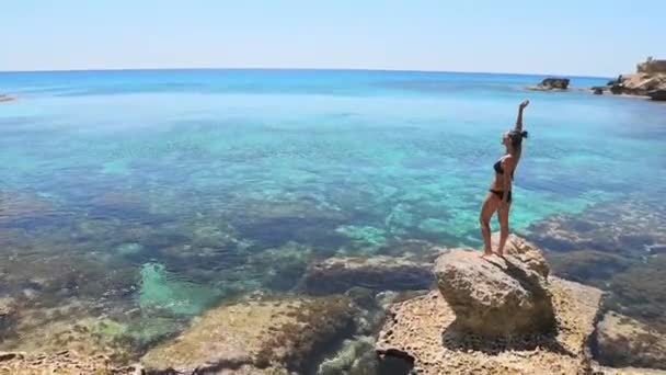 Beautiful caucasian woman stand on viewpoint rock enjoy crystal clear waters and mediterranean seascape panorama on summer holiday vacation. Happiness and travel explore concept - Footage, Video