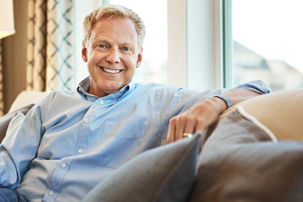 Retirement is a great time to relax. Portrait of a happy mature man relaxing on the sofa at home - Foto, Bild