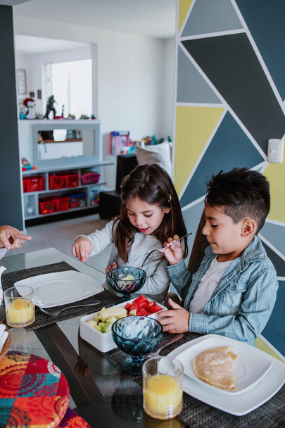 Latin család fia és lánya reggelizik és mexikói étel otthon Mexikóban, spanyol gyerekek Latin-Amerikában - Fotó, kép