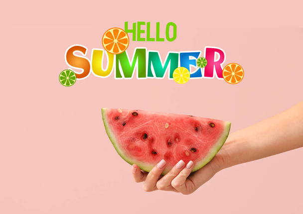 Hand mit Stück reife Wassermelone und Text HELLO, SOMMER auf rosa Hintergrund - Foto, Bild