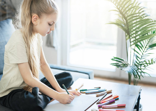 Gyermek lány rajzol színes ceruzákkal otthon. Ökológia koncepció, festészet föld.  - Fotó, kép